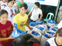 Student volunteers distribute bags of clothes.