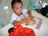 Three-year old Joemarie Llamelo enjoys putting colors on his artwork.